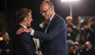 Emmanuel Macron i Friedrich Merz podają sobie ręce i uśmiechają się do siebie.