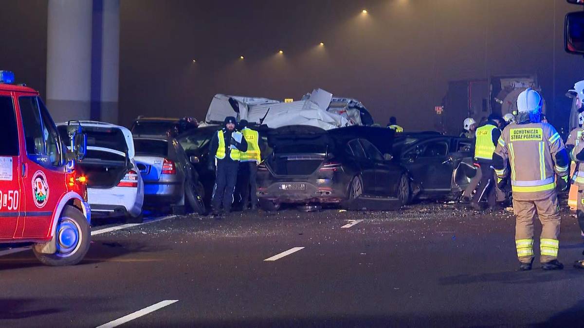 Na drodze w nocy, w gęstej mgle, doszło do karambolu z udziałem wielu samochod&oacute;w. Widać służby ratunkowe i zniszczone pojazdy.