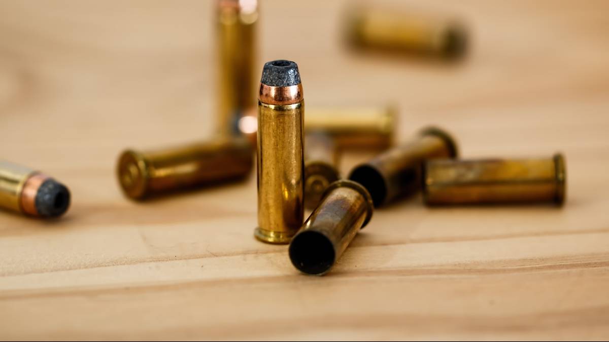 Zbliżenie na kilka nabojów kalibru .45 ACP leżących na drewnianej powierzchni.