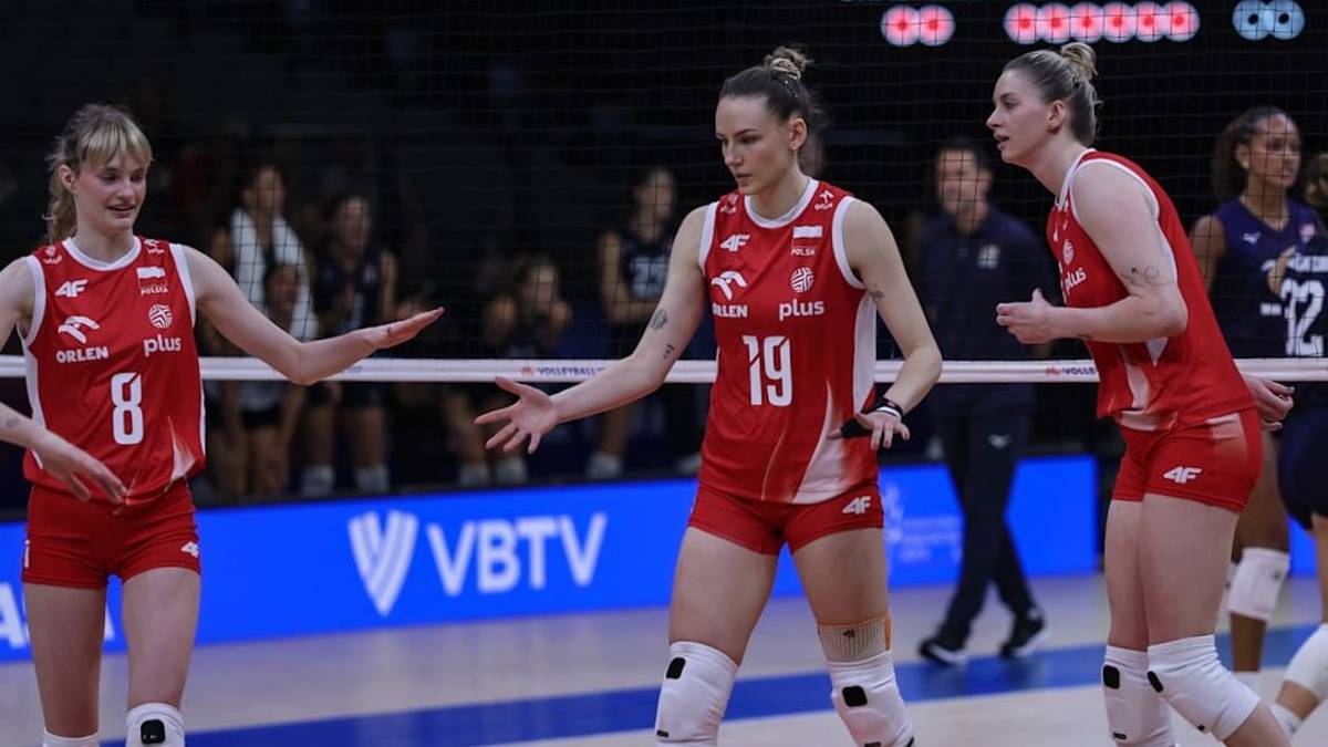 Trzy siatkarki w czerwonych strojach z białymi detalami na boisku.