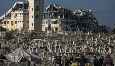 Grupa ludzi w pobliżu zniszczonych budynk&oacute;w i cmentarza.