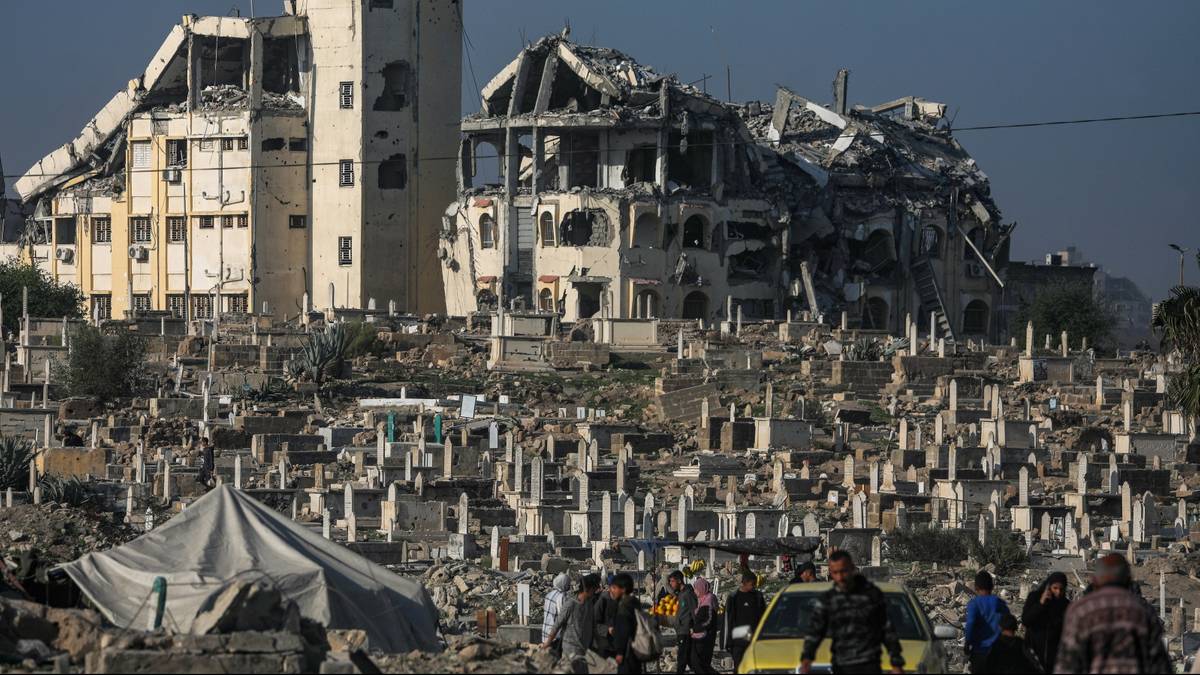 Grupa ludzi w pobliżu zniszczonych budynk&oacute;w i cmentarza.