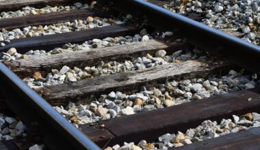 Zbliżenie na fragment tor&oacute;w kolejowych z widocznymi drewnianymi podkładami i kamiennym podsypiskiem.