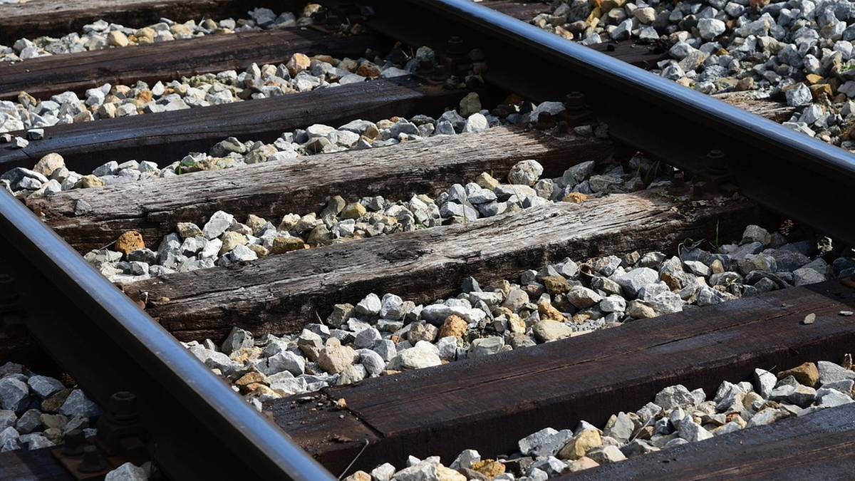 Zbliżenie na fragment tor&oacute;w kolejowych z widocznymi drewnianymi podkładami i kamiennym podsypiskiem.