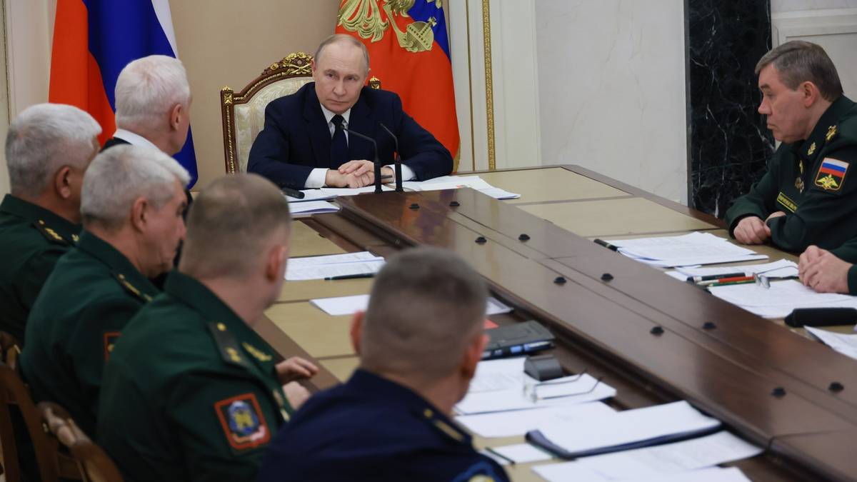 Władimir Putin siedzi przy stole konferencyjnym, rozmawiając z grupą rosyjskich dow&oacute;dc&oacute;w wojskowych.