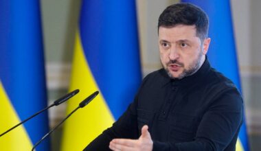 Wołodymyr Zełenski, prezydent Ukrainy, przemawia podczas konferencji prasowej, na tle flag Ukrainy.