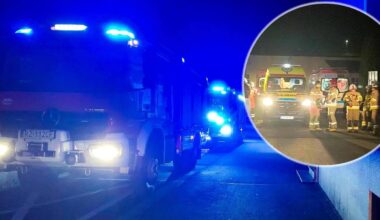 Straż pożarna i pogotowie ratunkowe na miejscu zdarzenia w nocy, z zapalonymi niebieskimi światłami.