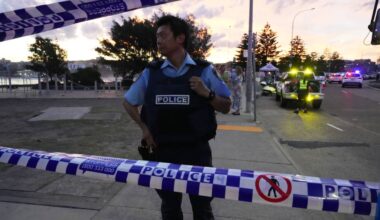 Policjant w kamizelce "POLICE" stoi za taśmą policyjną.