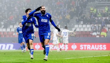 Piłkarze w niebieskich strojach świętują zdobycie bramki na zielonej murawie stadionu, z trybunami pełnymi kibic&oacute;w w tle.