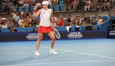 Tenisistka w stroju sportowym świętuje na korcie tenisowym, w tle publiczność i bandy reklamowe.