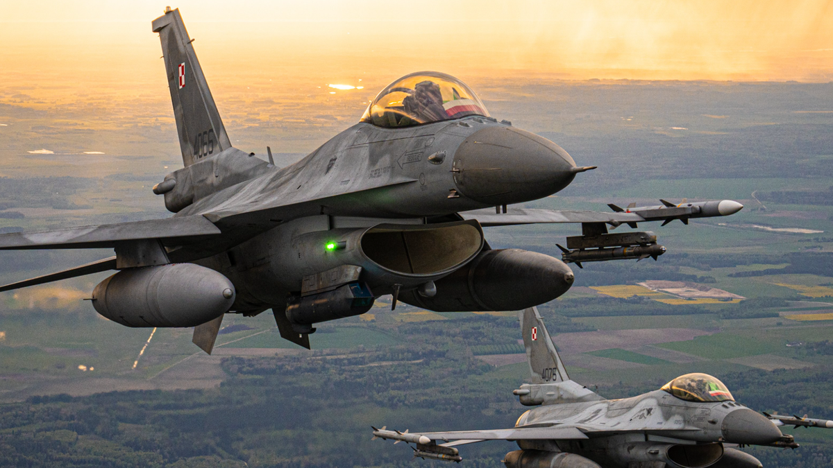 Dwa myśliwce F-16 lecące w formacji podczas zachodu słońca.