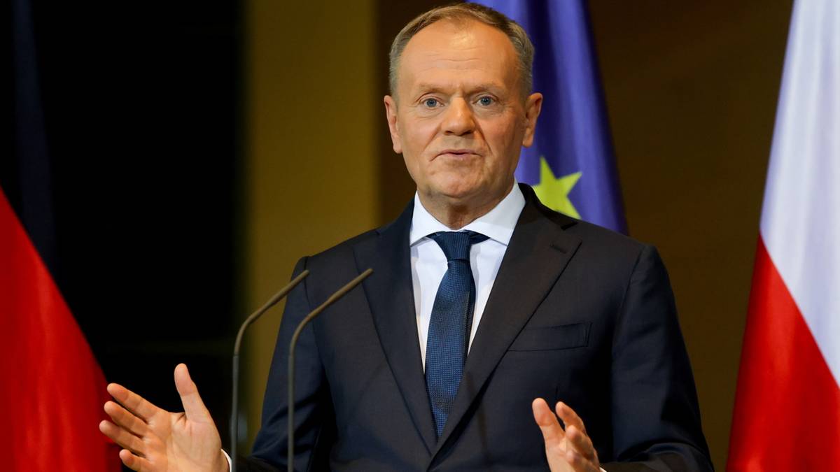 Donald Tusk, polityk w ciemnym garniturze i niebieskim krawacie, przemawia za mównicą. Za nim widoczne są flagi Polski i Niemiec.