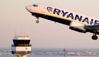 Samolot linii Ryanair startujący z lotniska, obok wieża kontroli lotów.