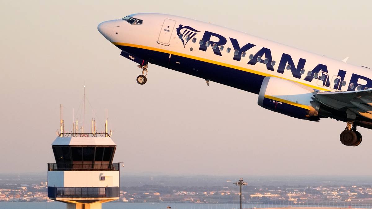Samolot linii Ryanair startujący z lotniska, obok wieża kontroli lotów.