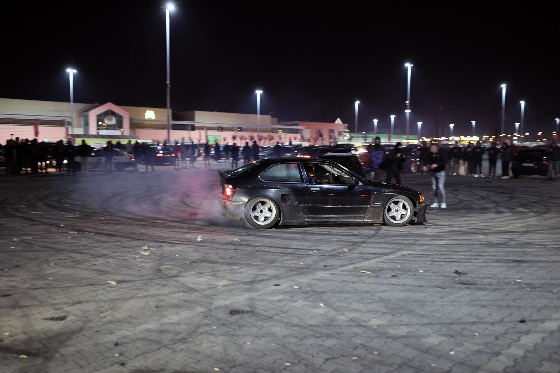 Nielegalny zlot samochodowy. Drift na parkingu pod supermarketem