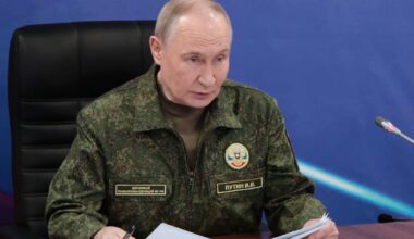 Władimir Putin w mundurze wojskowym siedzi przy biurku i przegląda dokumenty.