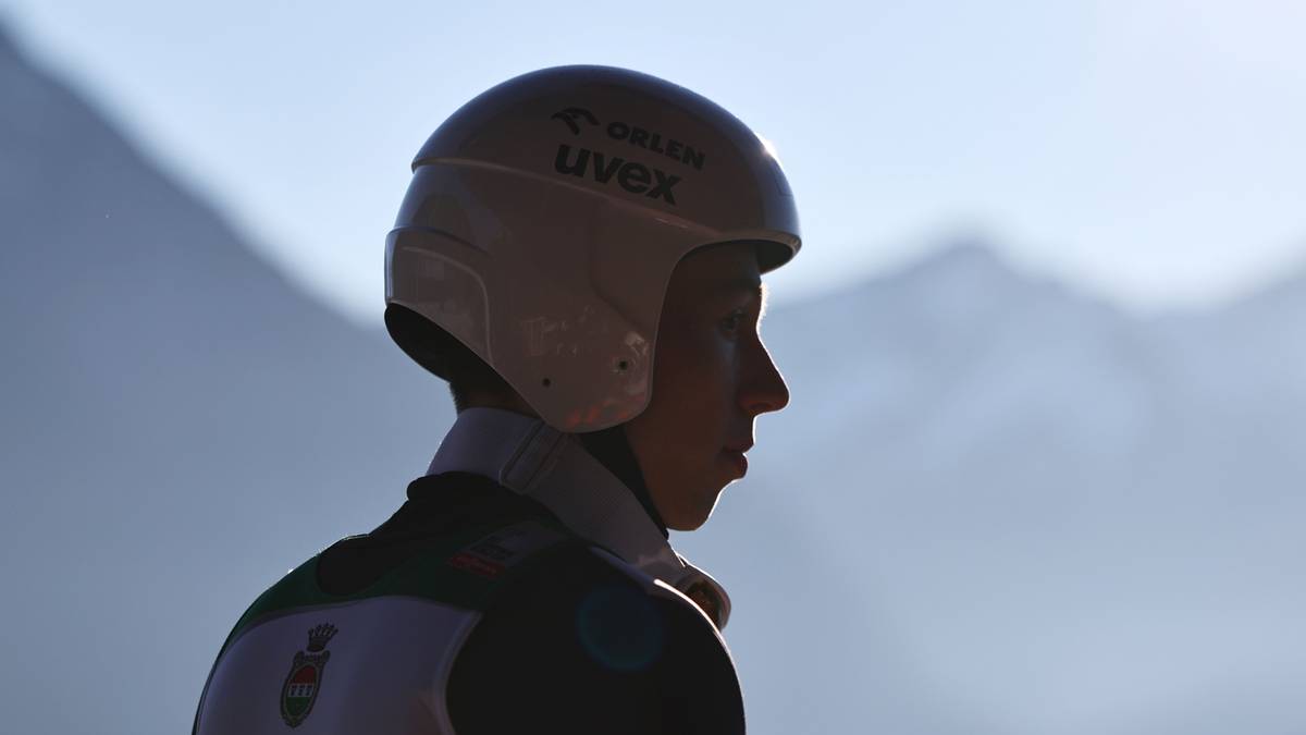 Sylwetka skoczka narciarskiego w kasku na tle g&oacute;r.