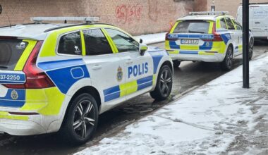 Dwa radiowozy policyjne zaparkowane na zaśnieżonej ulicy w Szwecji.