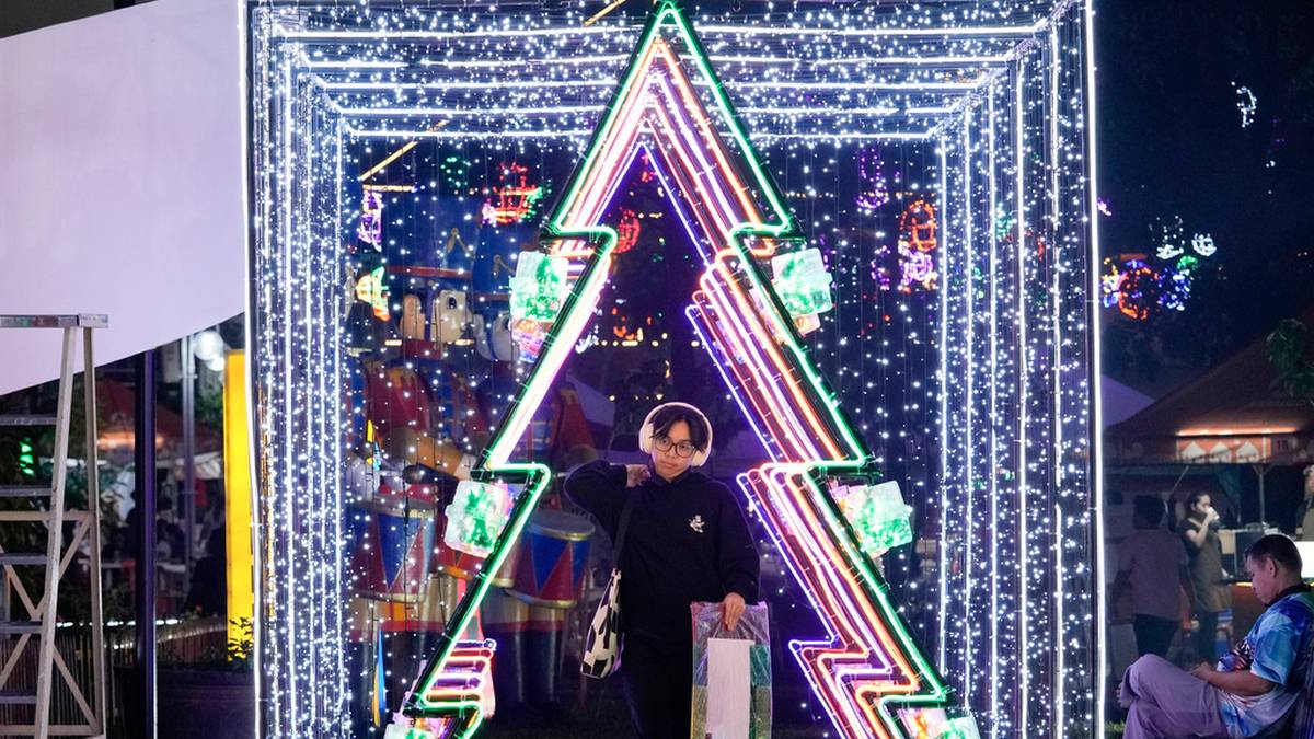 Osoba przechodzi przez ozdobioną światłami choinkę bożonarodzeniową.