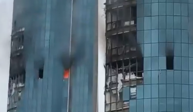 Uszkodzony ogniem i dymem wieżowiec Grozny-City w Groznym, z widocznymi wypalonymi oknami i fragmentami fasady.