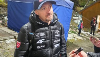 Piotr Żyła, polski skoczek narciarski, ubrany w kurtkę z logo sponsora, udziela wywiadu.