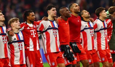 Piłkarze w czerwono-białych strojach stoją obok siebie, patrząc w górę.