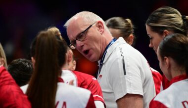 Trener piłki ręcznej Polski mężczyzna w okularach przemawia do zawodniczek w czerwonych strojach.