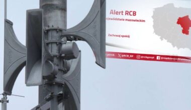 Fragment syren alarmowych oraz tablica informacyjna z komunikatem "Alert RCB" i mapą Polski z zaznaczonym wojew&oacute;dztwem mazowieckim.
