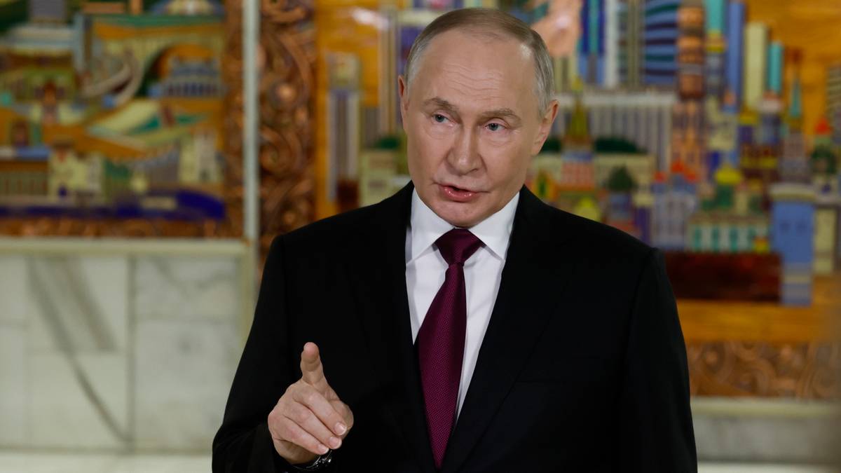 Władimir Putin w garniturze i krawacie wskazuje palcem.