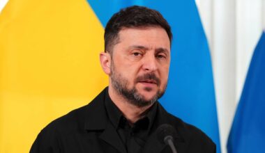 Wołodymyr Zełenski, prezydent Ukrainy, stoi przed flagami Ukrainy i Rosji.