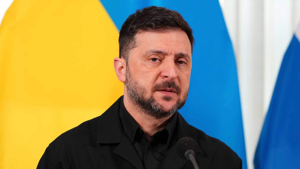 Wołodymyr Zełenski, prezydent Ukrainy, stoi przed flagami Ukrainy i Rosji.