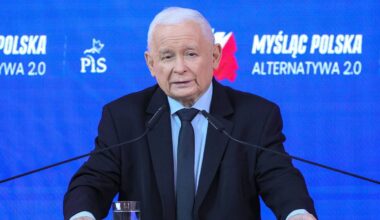 Jarosław Kaczyński przemawia przy m&oacute;wnicy, na tle baner z hasłem PiS.