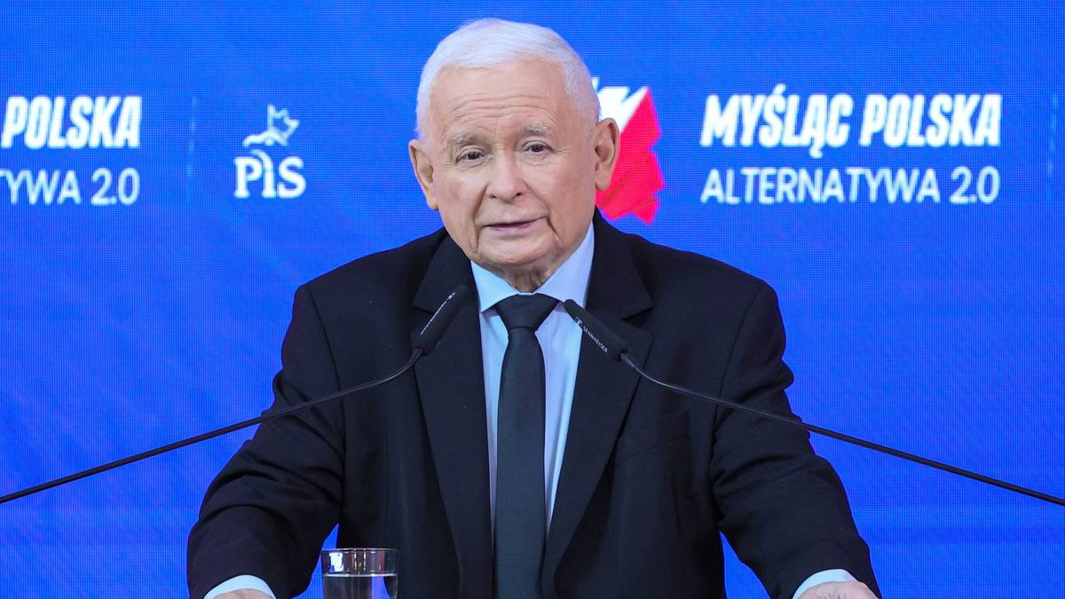 Jarosław Kaczyński przemawia przy m&oacute;wnicy, na tle baner z hasłem PiS.