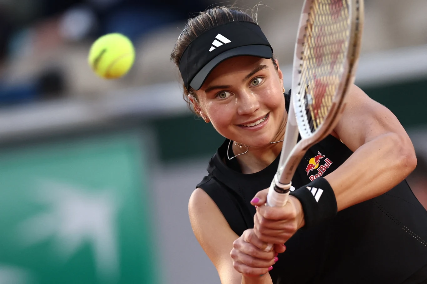 Tenisistka podczas odbicia piłki forehandem, skupiona twarz w dynamicznym ujęciu, sportowy strój, widoczna rakieta tenisowa oraz piłka w ruchu, tło rozmyte co podkreśla postać i akcję.