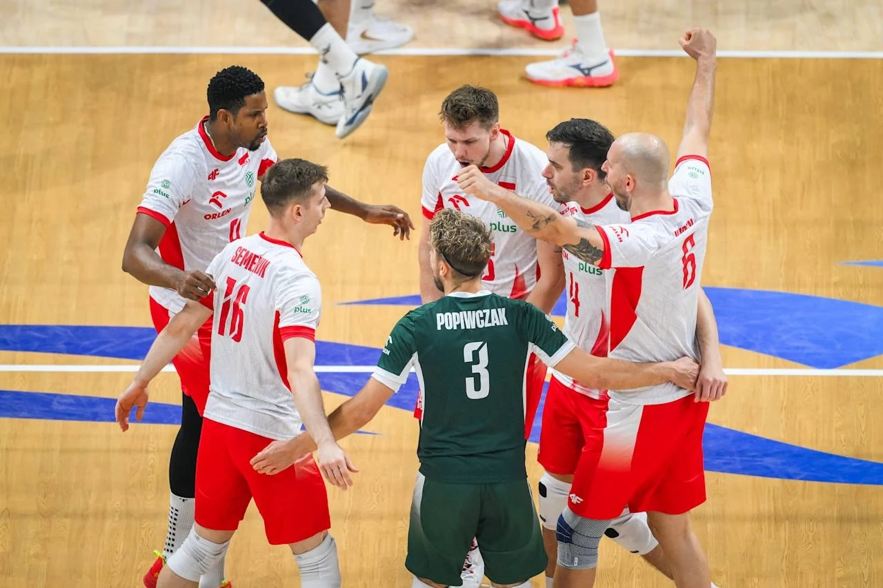 Zawodnicy reprezentacji Polski w siatkówce świętują zdobycie punktu podczas meczu, tworząc zwartą grupę na środku boiska, ubrani w sportowe stroje w biało-czerwonych barwach, widoczny jest także libero w zielonym stroju