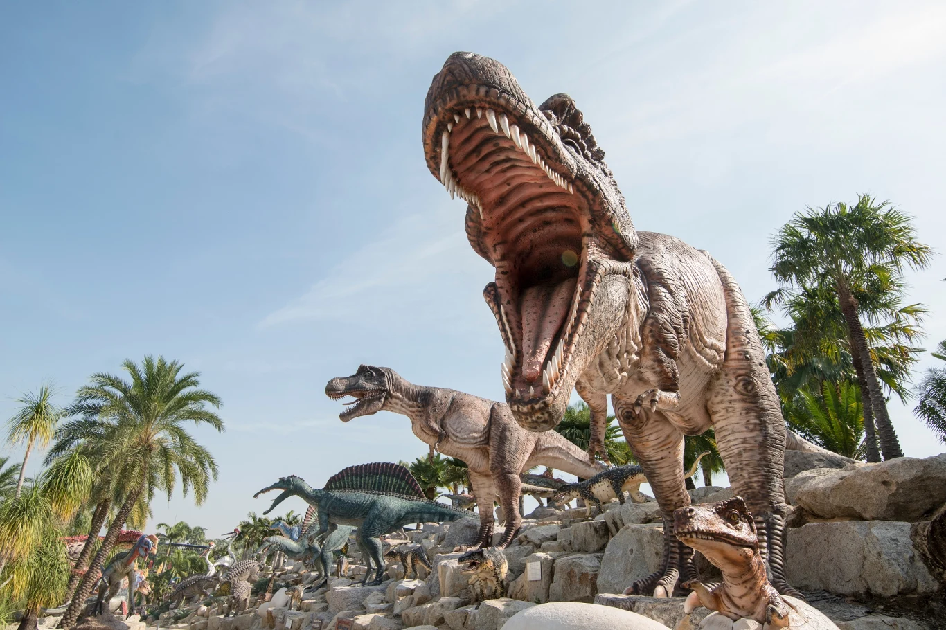 Drapieżne dinozaury polowały na terenach okresowych mokradeł w dawnym Chile Grupa realistycznych modeli dinozaurów stojących na skałach w otoczeniu tropikalnych roślin, na pierwszym planie duży dinozaur z szeroko otwartą paszczą, dalej inne prehistoryczne gady.