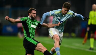 Grupa piłkarzy w jasnych strojach drużyny Juventus świętuje zdobycie bramki, jeden z zawodników jest mocno obejmowany przez kolegów z zespołu, wszyscy wyrażają radość i entuzjazm.