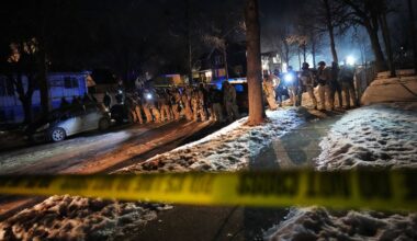 Grupa funkcjonariuszy w mundurach stoi na ulicy nocą, przed nimi znajduje się taśma policyjna.