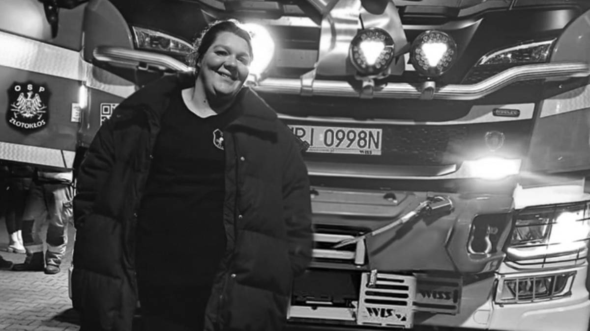 Zdjęcie kobiety w zimowej kurtce, stojącej przed wozem strażackim