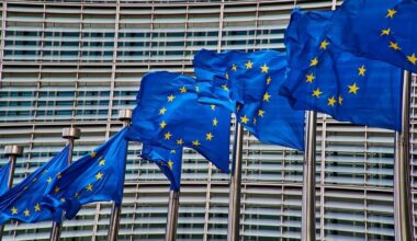 Flagi Unii Europejskiej powiewające przed budynkiem.