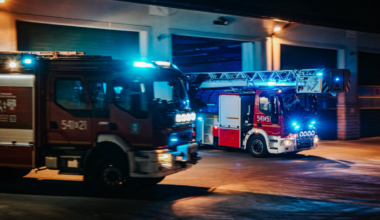 Dwa wozy strażackie z włączonymi światłami alarmowymi.