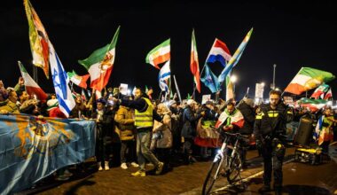 Tłum ludzi z flagami narodowymi podczas nocnej manifestacji.