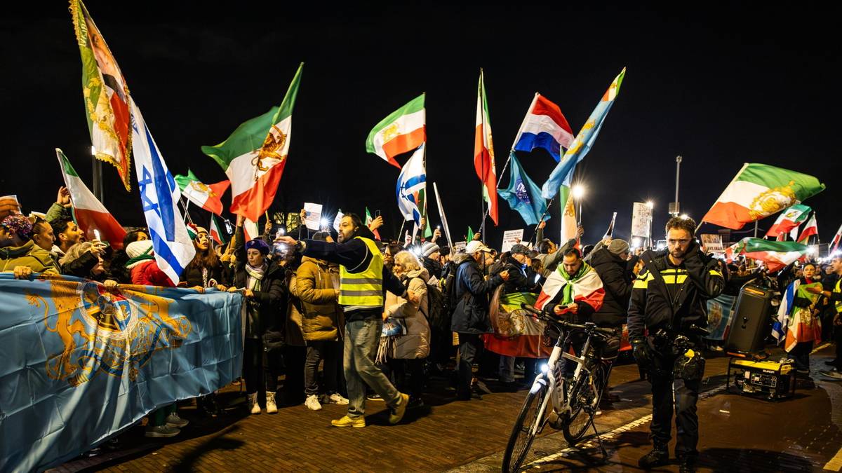 Tłum ludzi z flagami narodowymi podczas nocnej manifestacji.
