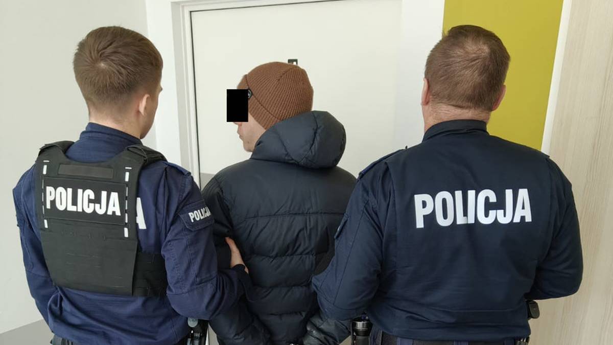 Policjanci prowadzą zatrzymanego mężczyznę w kajdankach.