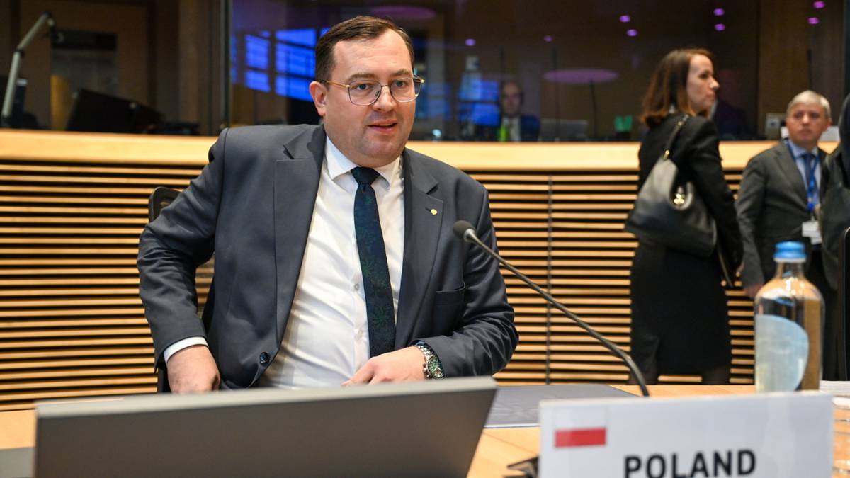 Minister rolnictwa Stefan Krajewski siedzi przy stole z laptopem i tabliczką "POLAND".