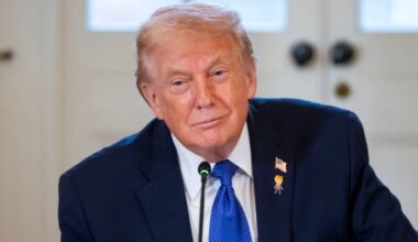 Donald Trump w ciemnym garniturze i niebieskim krawacie podczas spotkania.