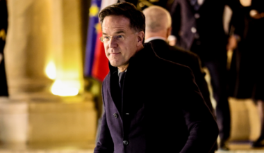 Mark Rutte, premier Holandii, w eleganckim płaszczu i okularach, idzie w kierunku kamery.