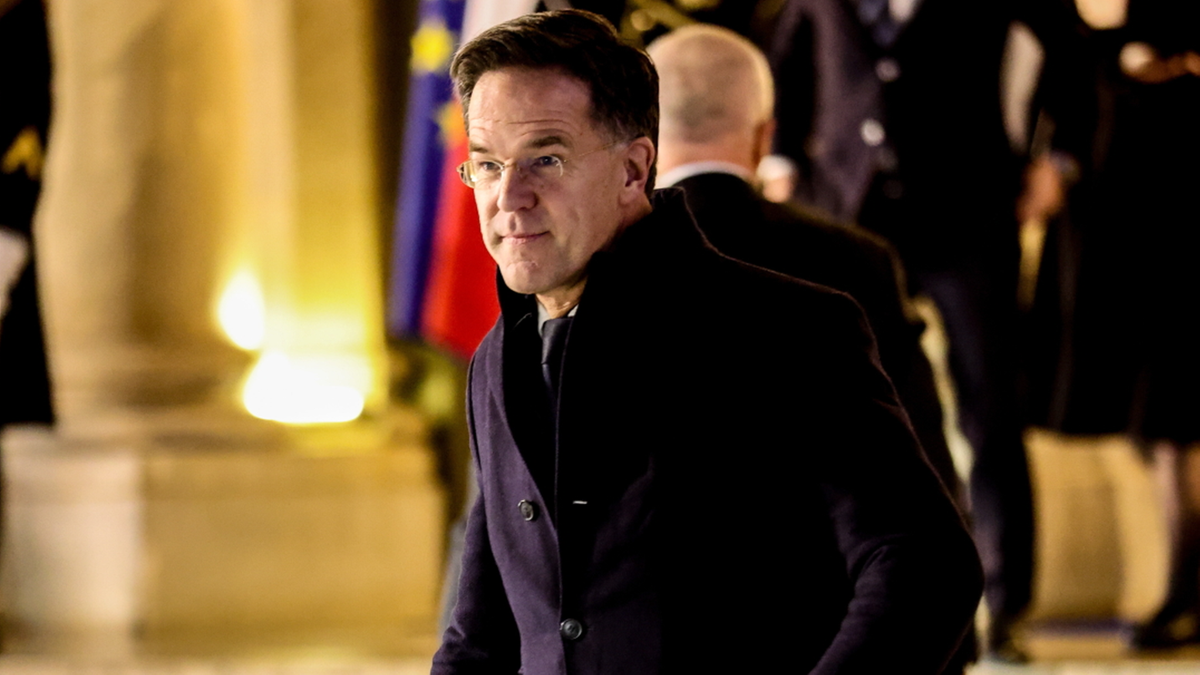 Mark Rutte, premier Holandii, w eleganckim płaszczu i okularach, idzie w kierunku kamery.