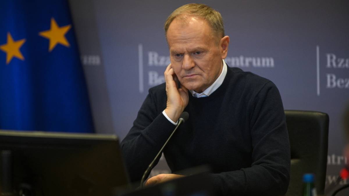 Donald Tusk siedzi przy biurku, rozmawiając przez telefon.