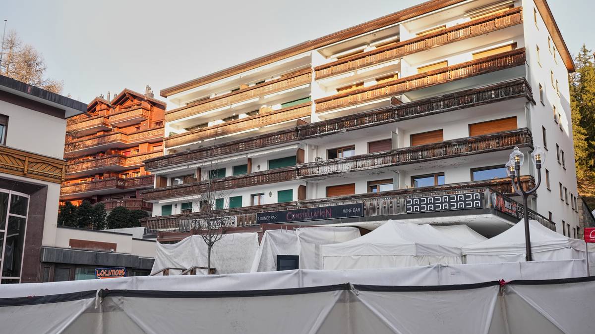 Budynek mieszkalny z białymi namiotami rozstawionymi przed nim, zasłaniającymi część fasady.